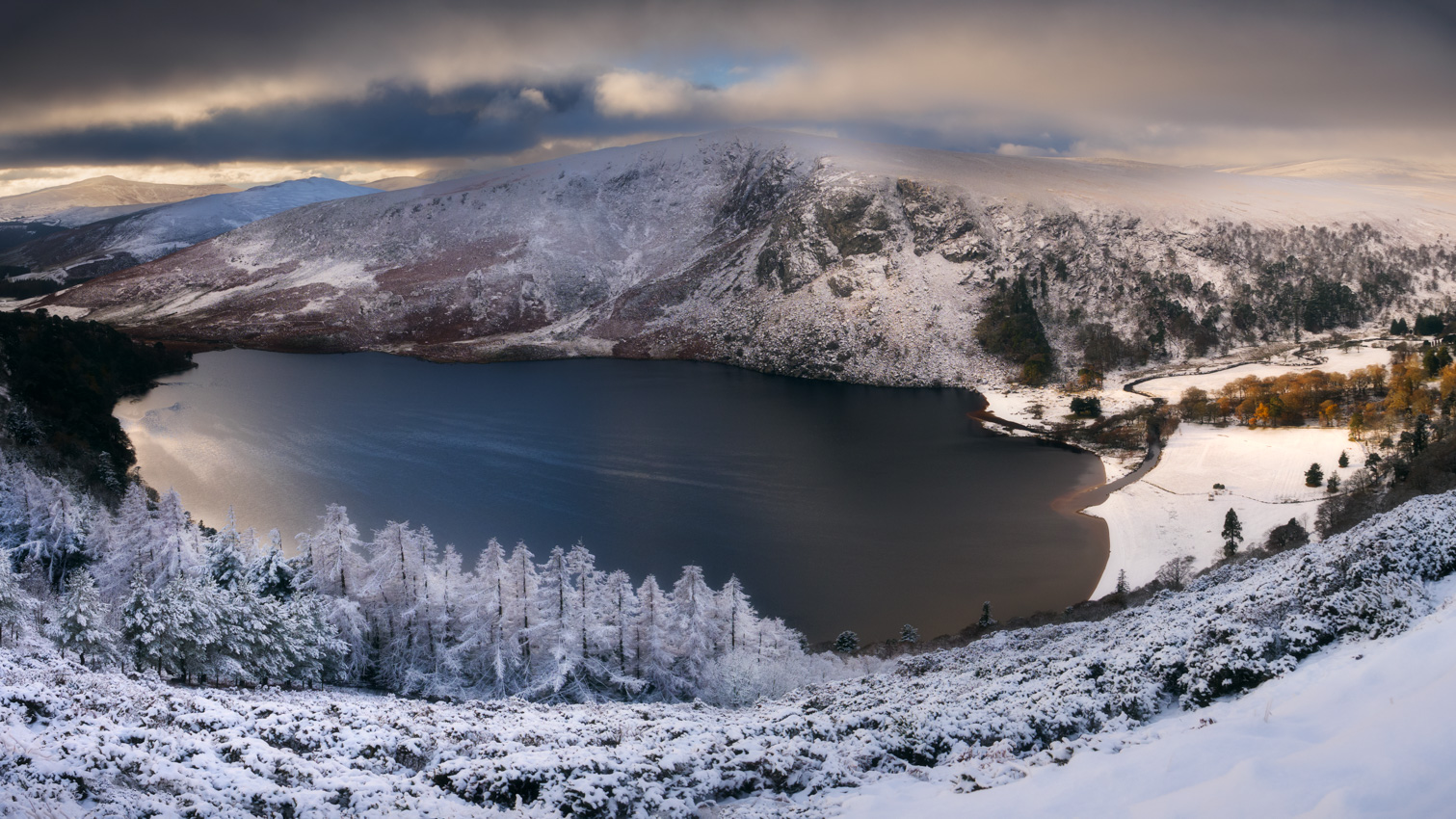 Panoramic view on Lough Tay covered by snow in winter conditions